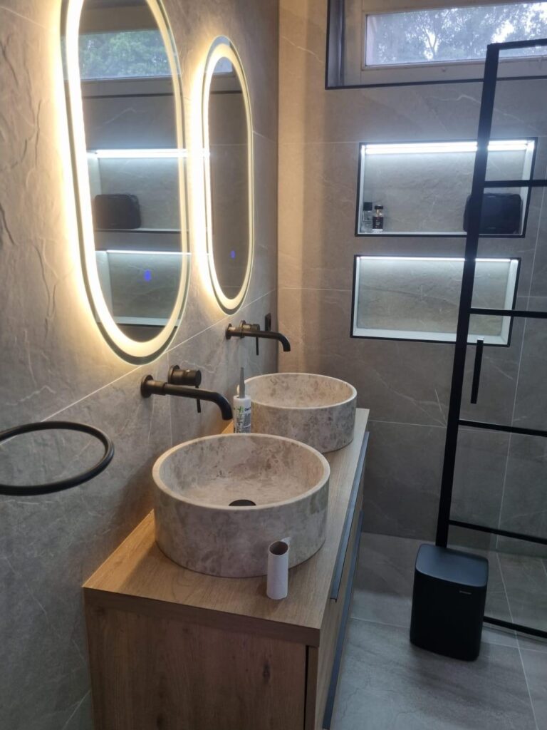 Badkamer met verlichte nissen, zwarte kranen en inloopdouche